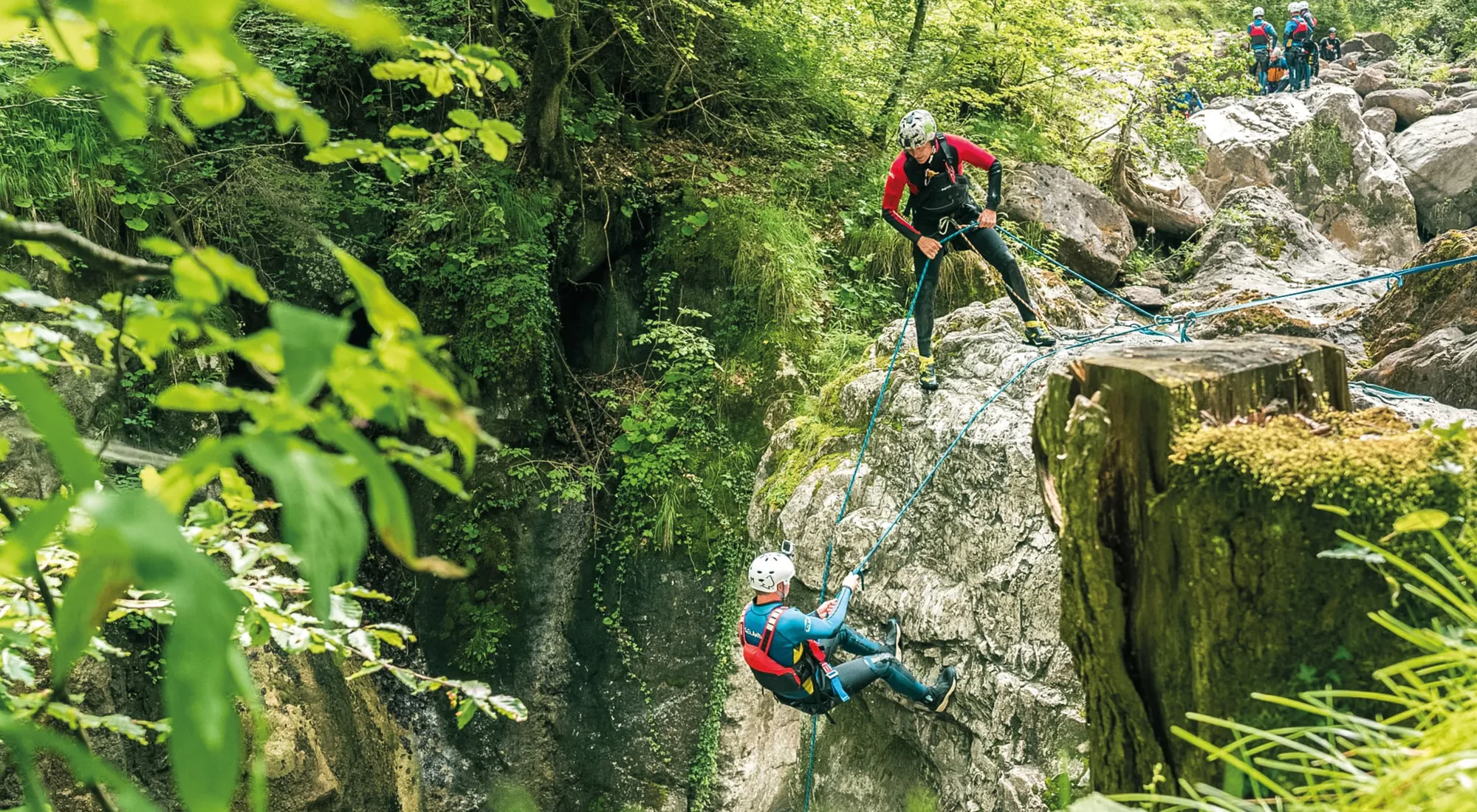 Canyoner beim Abseilen durch eine grüne, bemooste Schlucht bei Interlaken