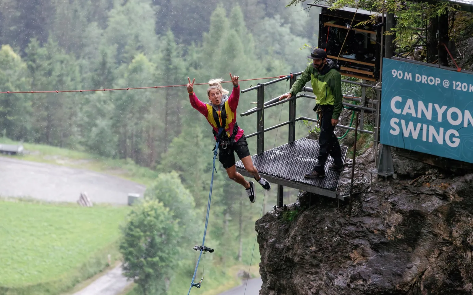 Jumper stepping off the Canyon Swing platform above a wooded gorge