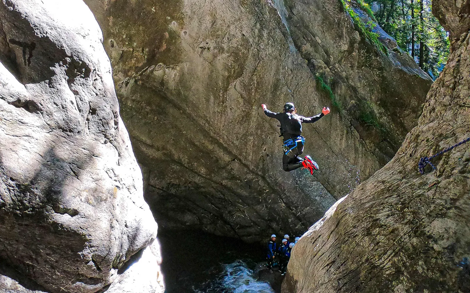 Canyoner seilt sich neben einem Wasserfall durch eine enge Felsschlucht ab