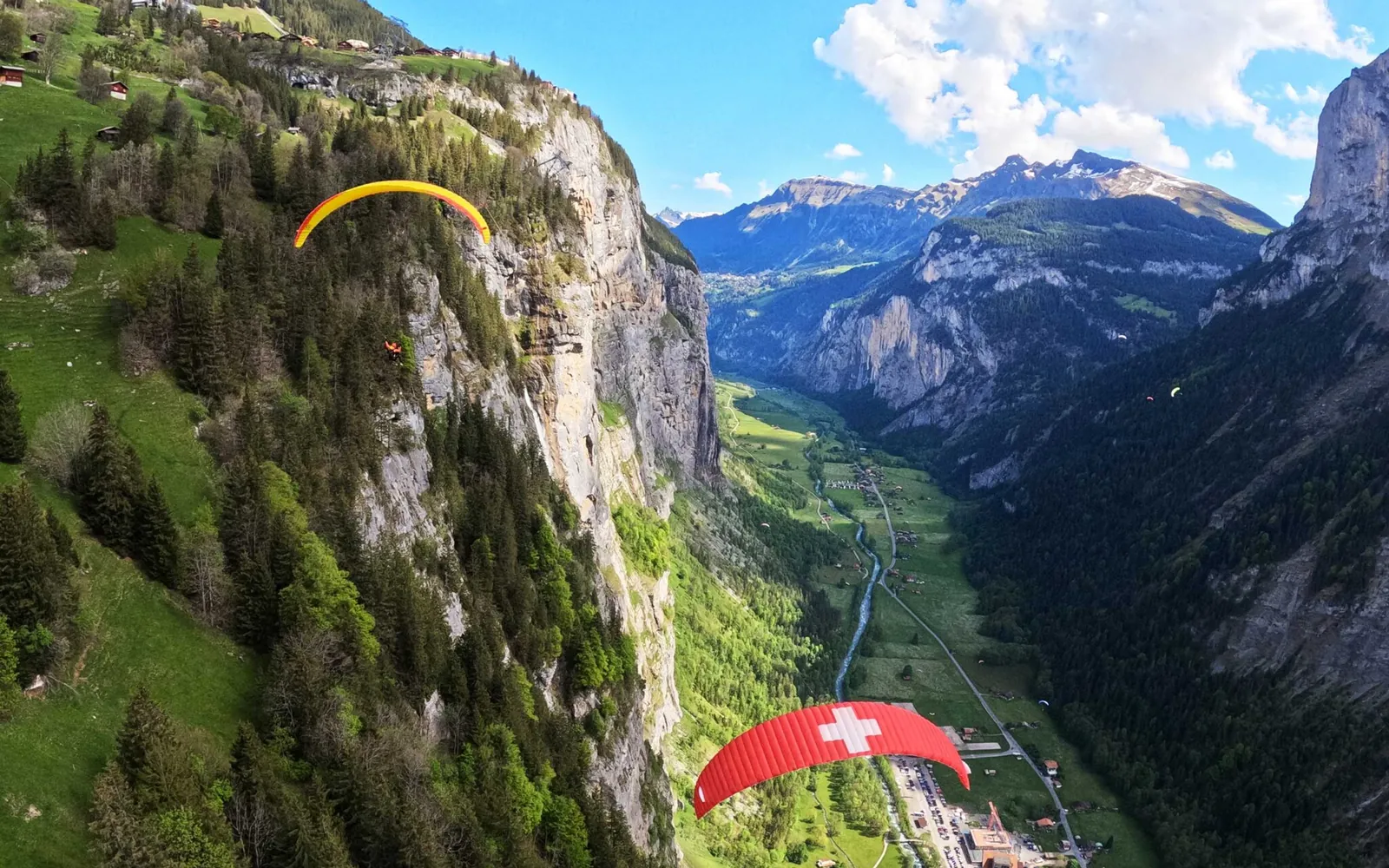 Zwei Tandem-Gleitschirme fliegen zwischen den Felswänden des Lauterbrunnentals