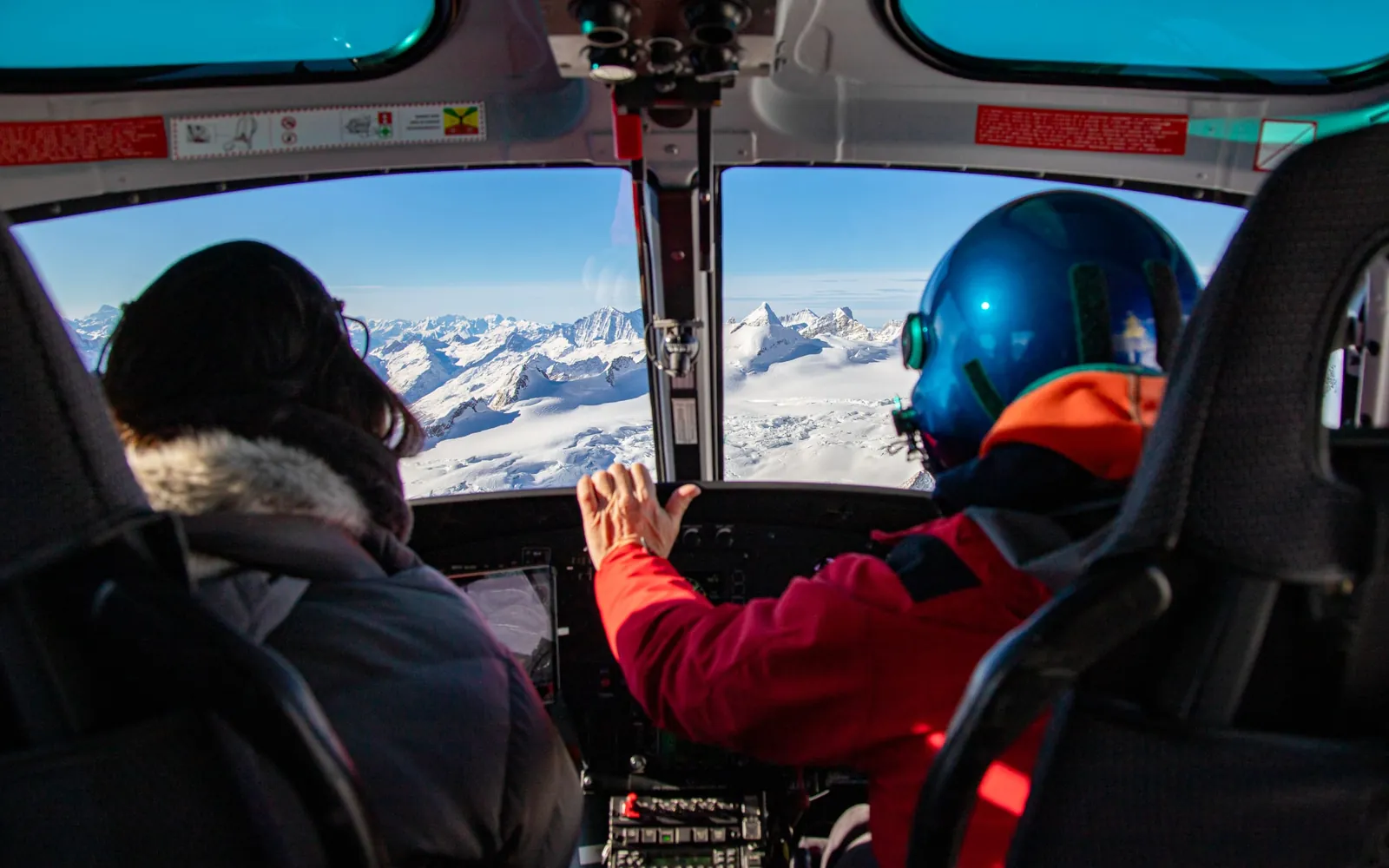Blick aus einem Helikoptercockpit auf verschneite Alpengipfel