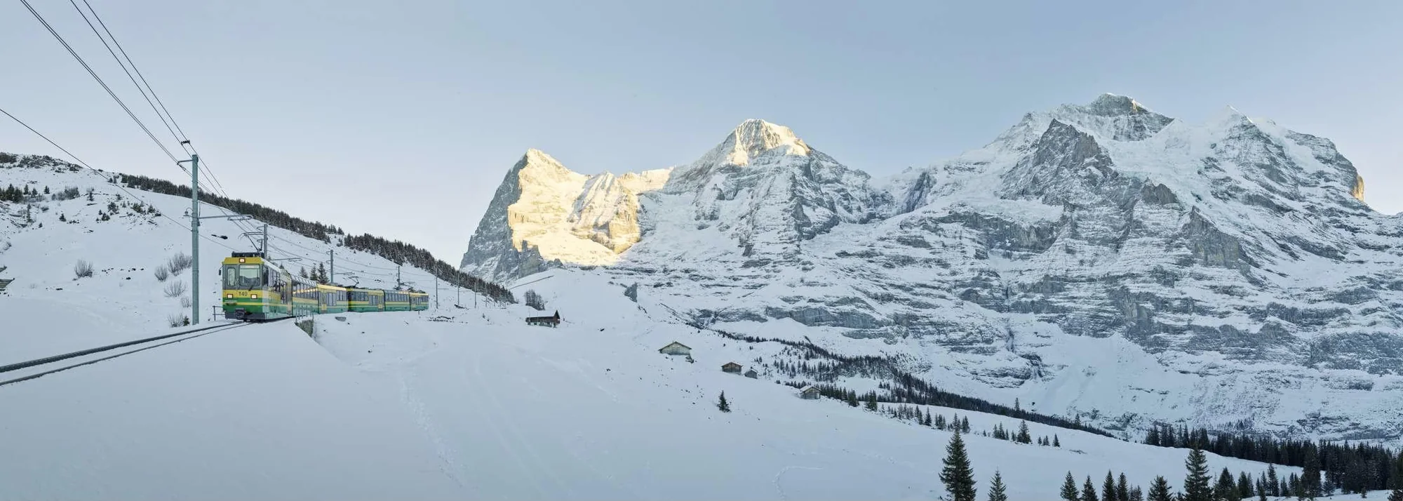 Wengernalpbahn train crossing deep snow below the Eiger, Mönch and Jungfrau at first light