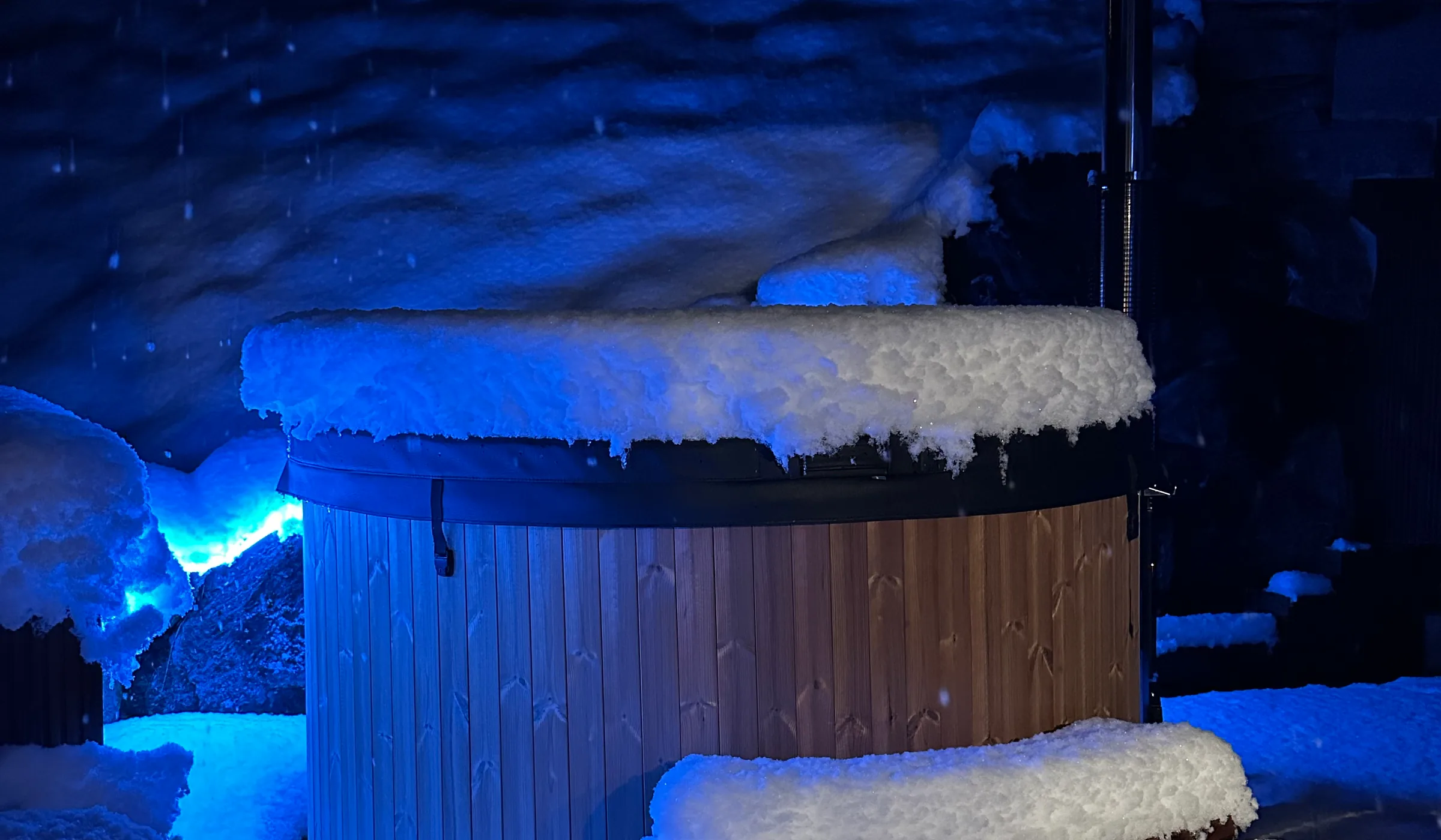Private wood-fired hot tub steaming at night below the floodlit Staubbach Falls, Chalet Staubbach