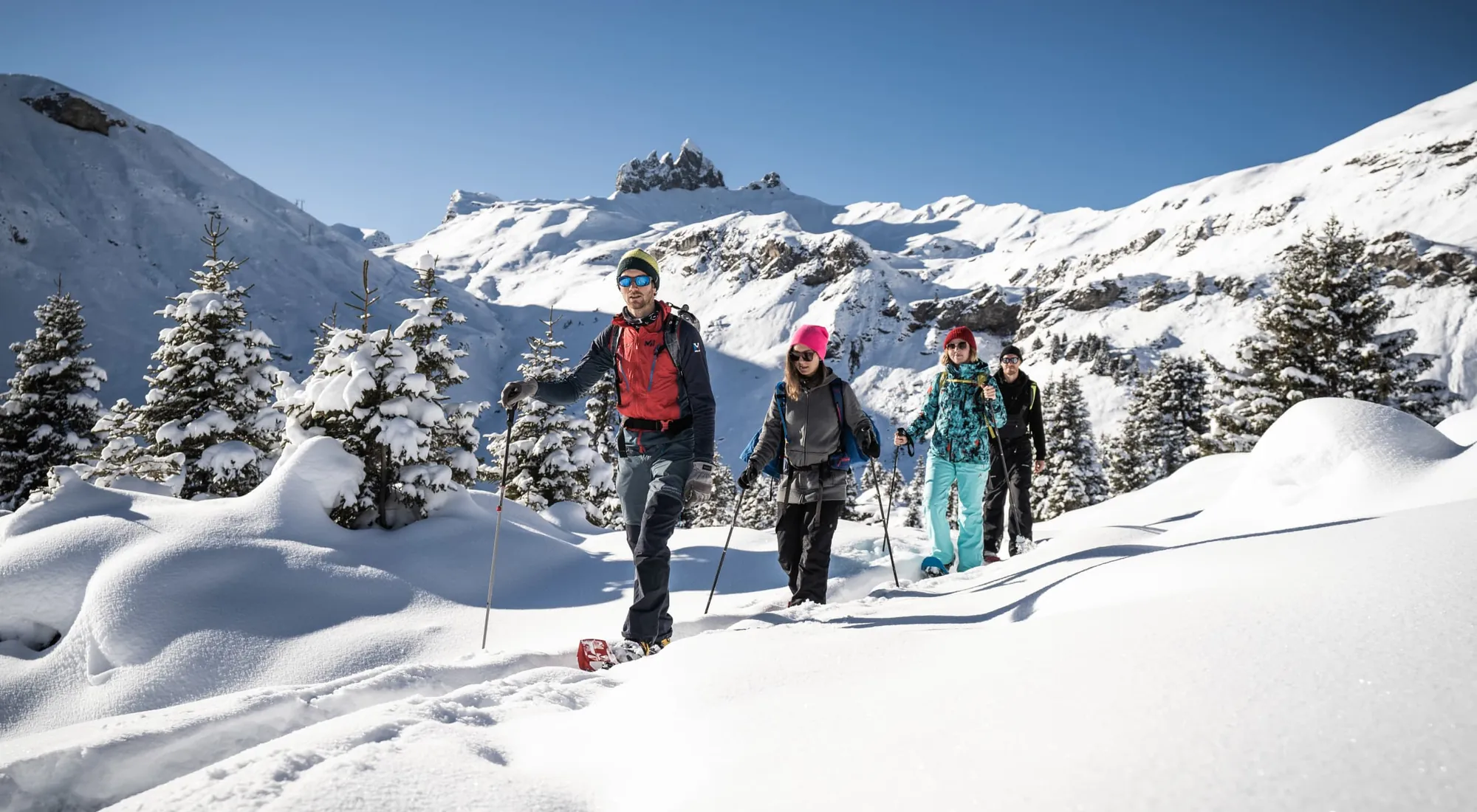 Group snowshoeing through deep snow under a blue sky in the Bernese Oberland